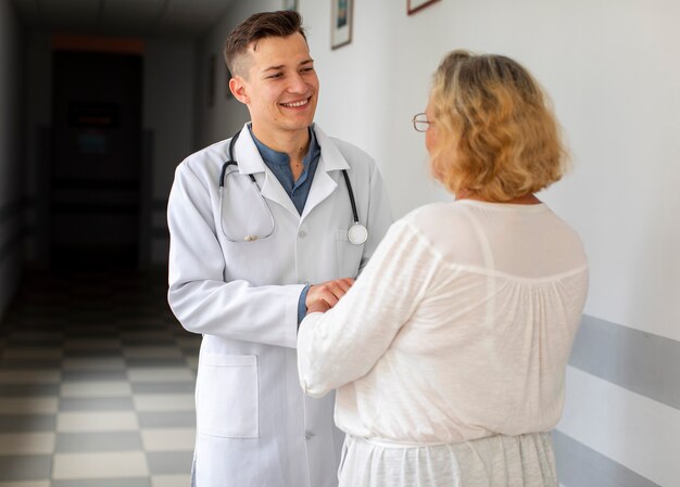 Young doctor talking with woman on hospital hall