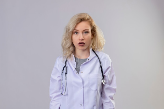 Young doctor wearing stethoscope in medical gown on white wall