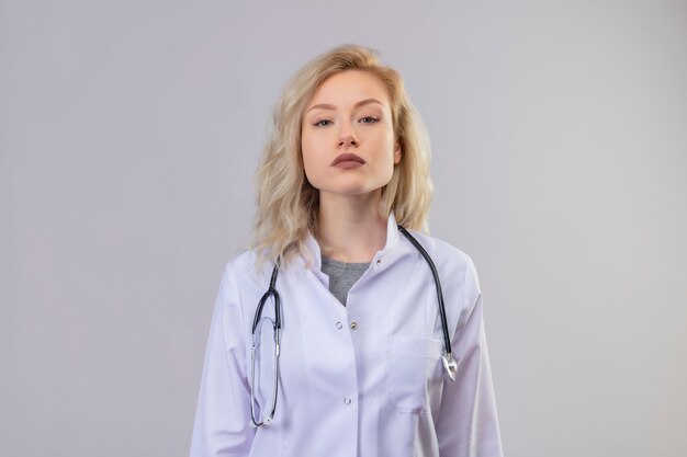 Young doctor wearing stethoscope in medical gown on white wall