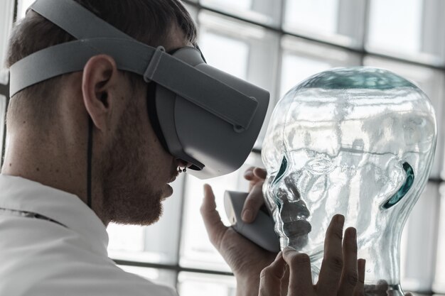A young doctor wearing VR goggles examining a mannequin in VR simulation - future technology concept