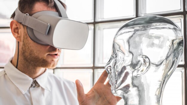 A young doctor wearing VR goggles examining a mannequin in VR simulation