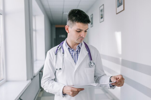 Young doctor with papers standing in clinic