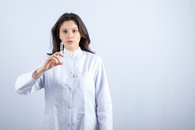 young doctor with syringe standing on white wall.