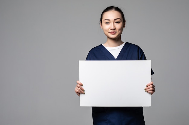 young doctor woman showing blank billboard, isolated on white wall