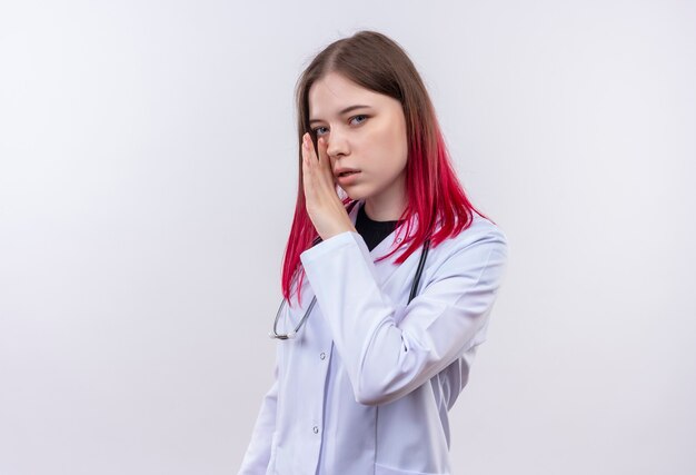  young doctor woman wearing stethoscope medical robe whispers on isolated white wall