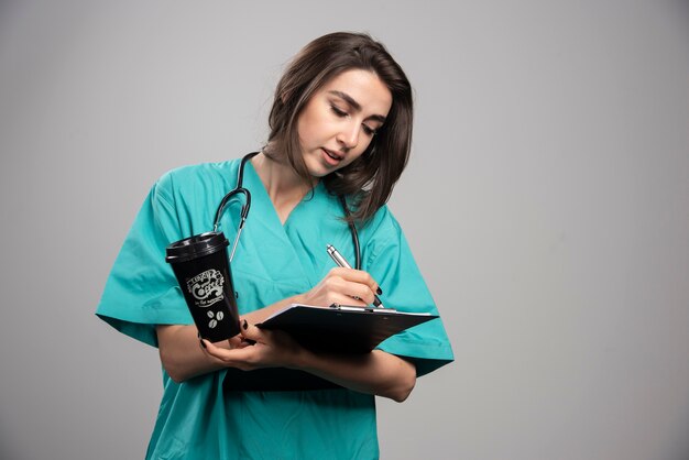 Young doctor writing notes on clipboard. 