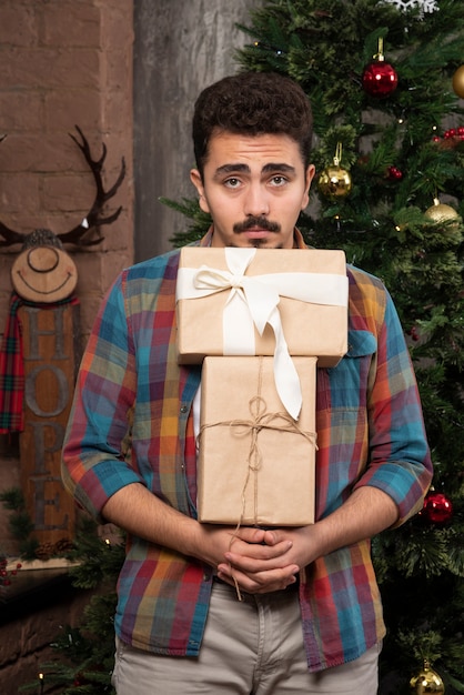 Young doubtful guy carrying gift box.