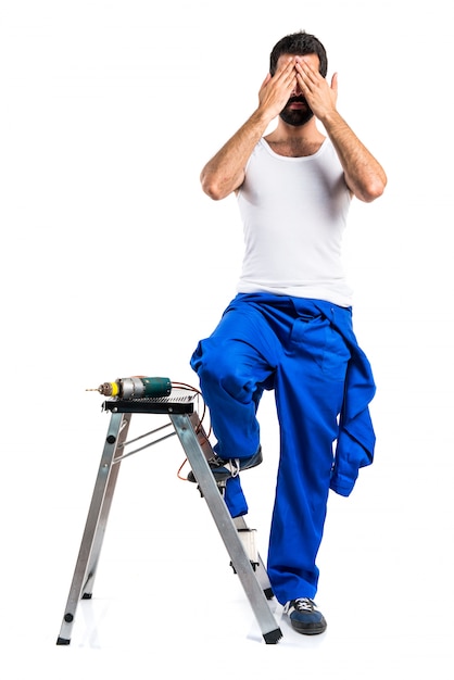 Free photo young electrical technician with a drill covering his eyes