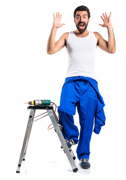 Young electrical technician with a drill doing surprise gesture