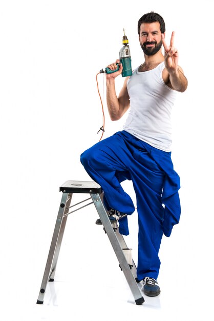 Young electrical technician with a drill making victory gesture