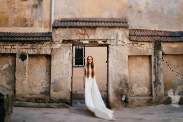 돌 고대 건물 위에 포즈를 취하는 긴 흰 드레스에 우아한 소녀