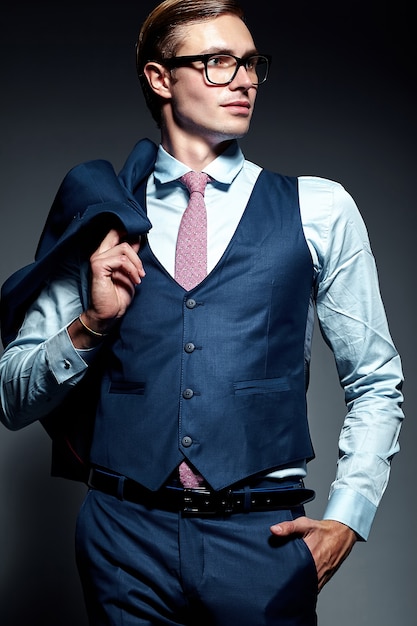 Young elegant handsome businessman male model in blue suit and fashionable glasses, posing in studio