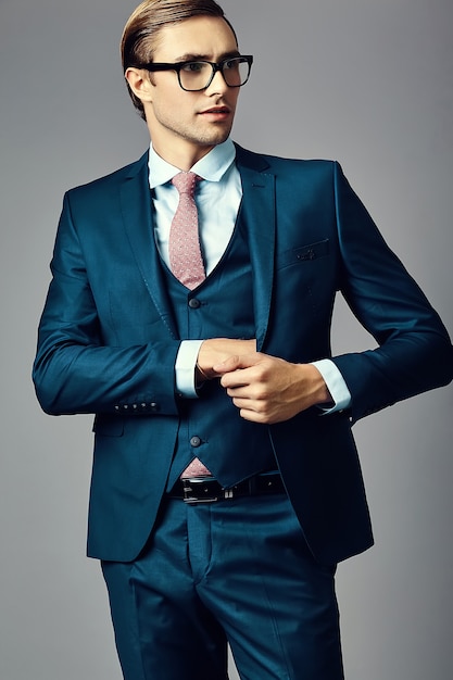 Young  elegant handsome  businessman male model in a suit and fashionable glasses, posing in studio