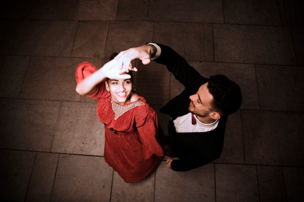 Young elegant man holding hand of dancing charming cheerful woman