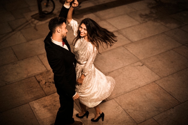 Young elegant man holding hand of whirling attractive cheerful woman