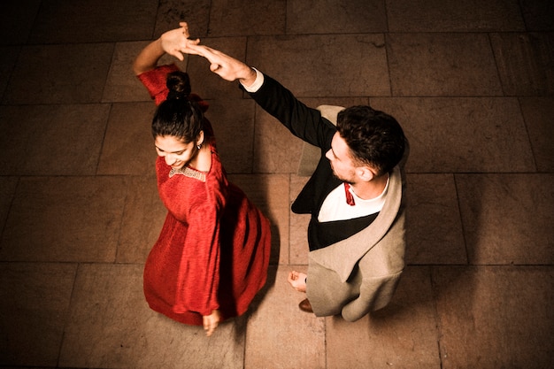 Free photo young elegant man holding hand of whirling charming cheerful woman