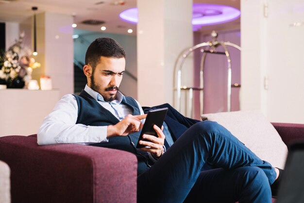 Young elegant man tapping tablet