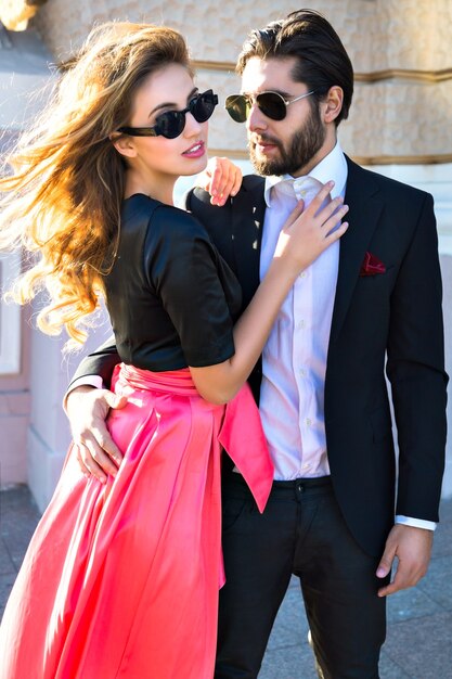 Young elegant sexy couple hugs on the street, wearing suit and glamour evening dress, enjoy their honeymoon vacation in Europe, luxury style, love, stylish lovers