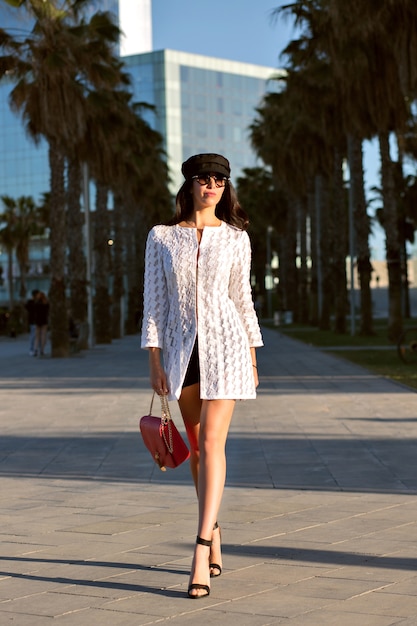 Young elegant woman walking alone , trendy elegant outfit and accessories, mid age sexy lady, toned colors, palms alleys.