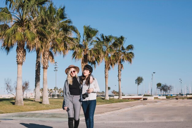 Young embracing stylish girls strolling