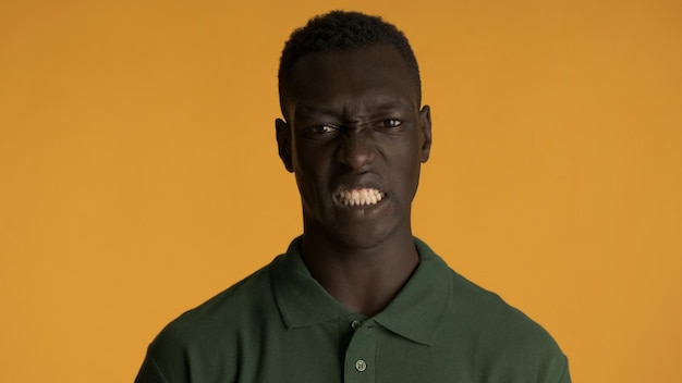 黄色の背景に分離されたカメラにうんざりしている若い感情的なアフリカ系アメリカ人の男