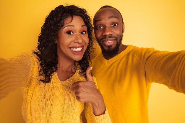 Молодой эмоциональный афро-американский мужчина и женщина в яркой повседневной одежде на желтом пространстве