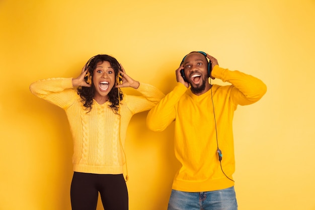 Young emotional african-american man and woman on yellow background