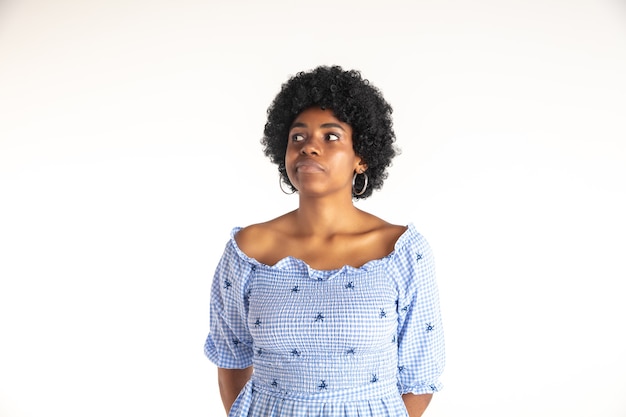 Young emotional african-american woman in blue dress. Facial expression, human emotions concept. Thoughtful, dreaming.