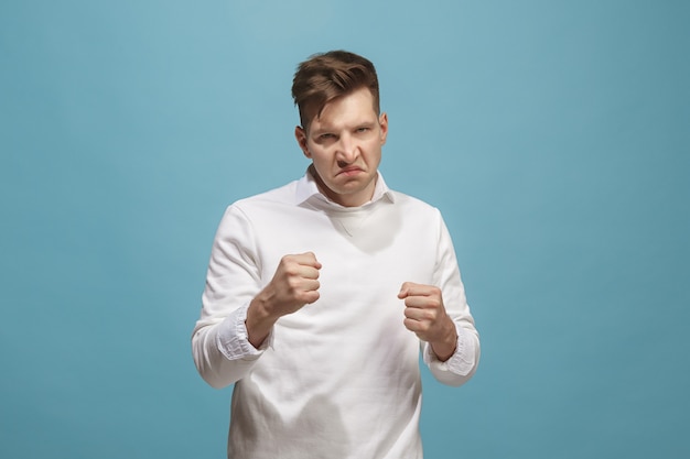 The young emotional angry man screaming on studio background