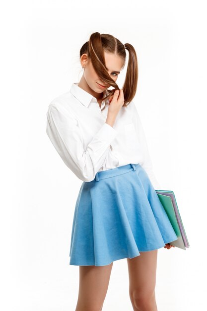 Young emotional girl in uniform posing, isolated on white wall