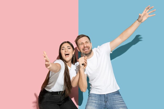 Young emotional man and woman on pink and blue wall