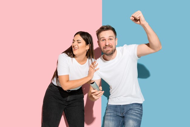 Young emotional man and woman on pink and blue wall