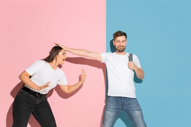 Young emotional man and woman on pink and blue wall