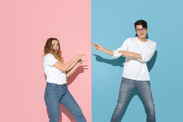 Young emotional man and woman on pink and blue