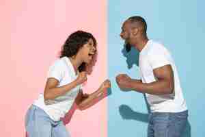 Free photo young emotional man and woman on pink and blue