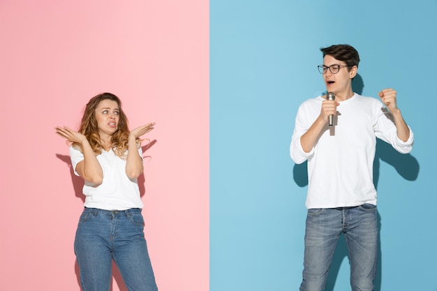 Young emotional man and woman on pink and blue