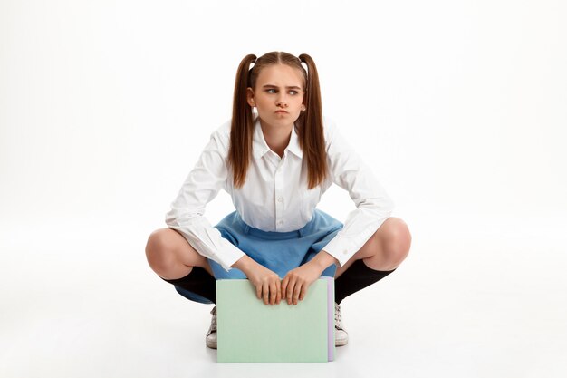 Young emotional pretty girl in uniform posing over white wall