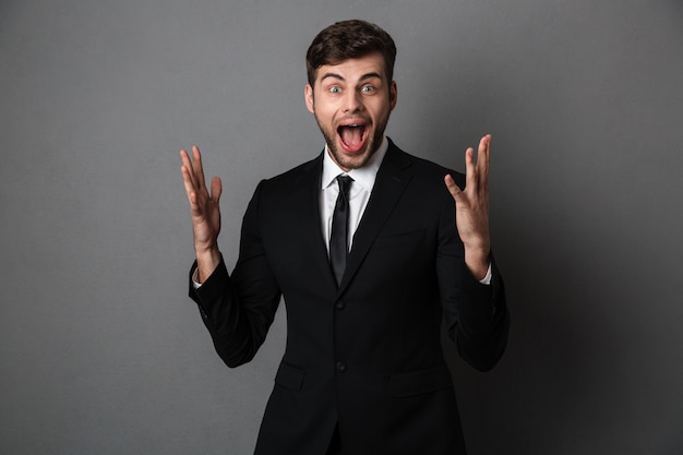 Free photo young emotional screaming businessman standing with opened palms,