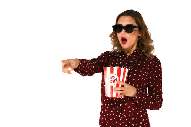 Young emotional woman with popcorn watching action movie in 3d glasses