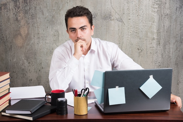 Young employee looking camera at the office desk.