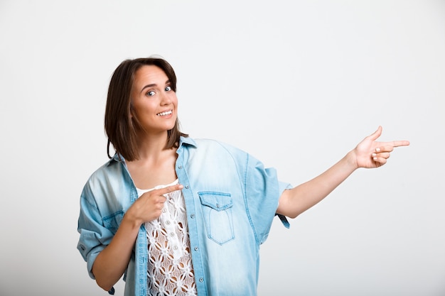 Young enthusiastic woman pointing right