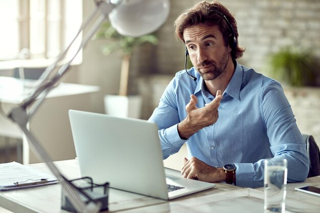 Young entrepreneur communicating with someone while having video conference in the office