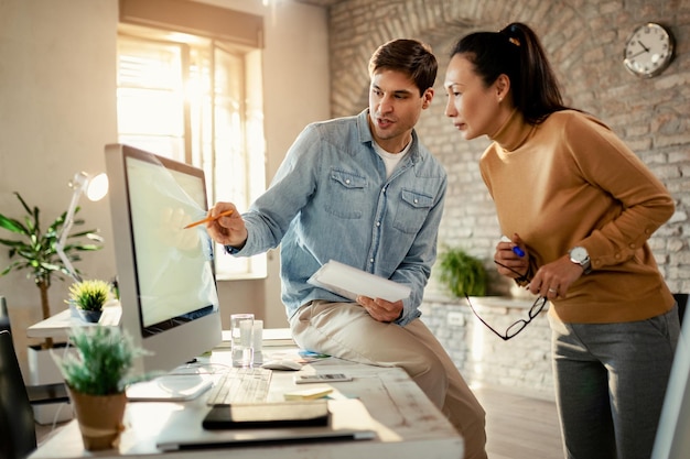 Young entrepreneur cooperating with female colleague while working on a computer in the office