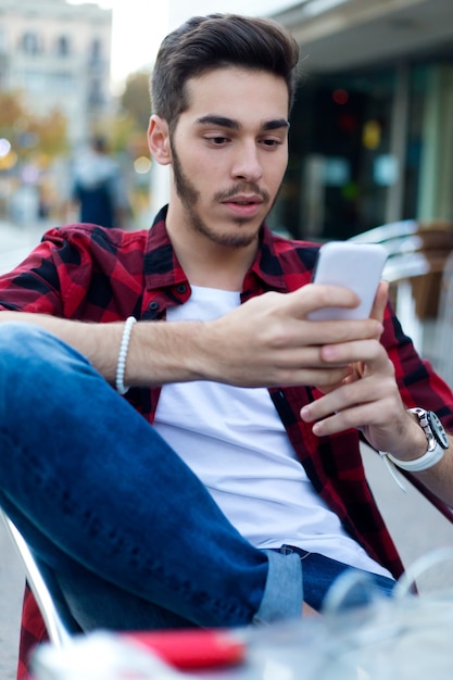 Foto gratuita giovane imprenditore con il suo telefono cellulare al coffee shop.