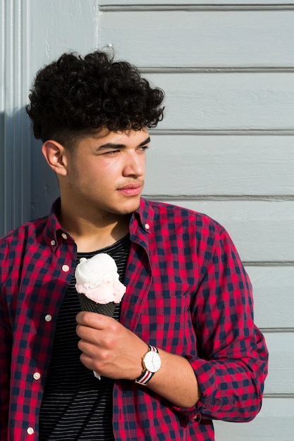 Free photo young ethnic curly man in plaid shirt with ice cream