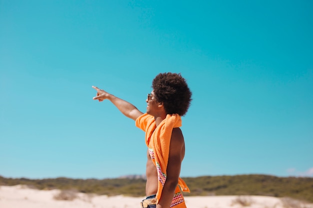 Молодой этнический человек, показывая пальцем вперед на пляже