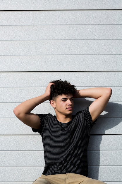 Young ethnic man touching curly hair