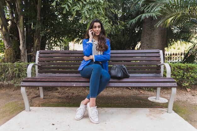 Young executive talking on the phone on a park bench