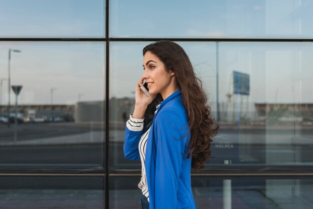 Young executive talking on the phone with glass building background