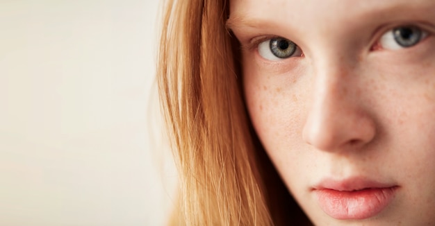 Young eyes girl beautiful redhead freckles woman face closeup portrait with healthy skin